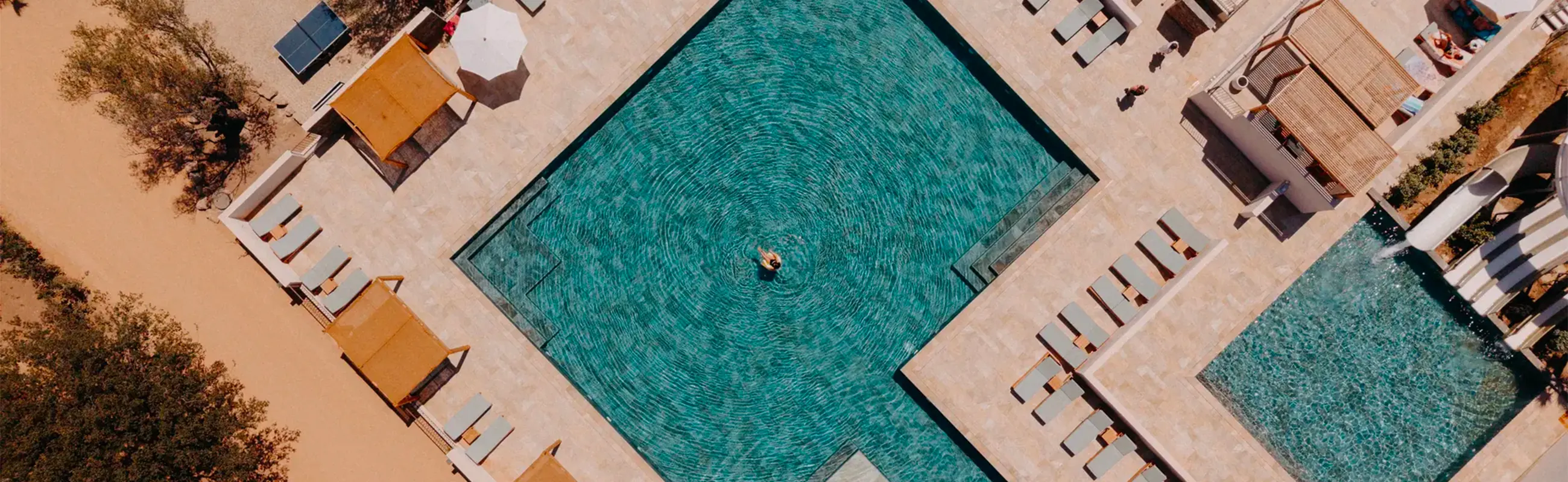 Vue aérienne de la grande piscine et des transats de l'espace aquatique du camping en Balagne.